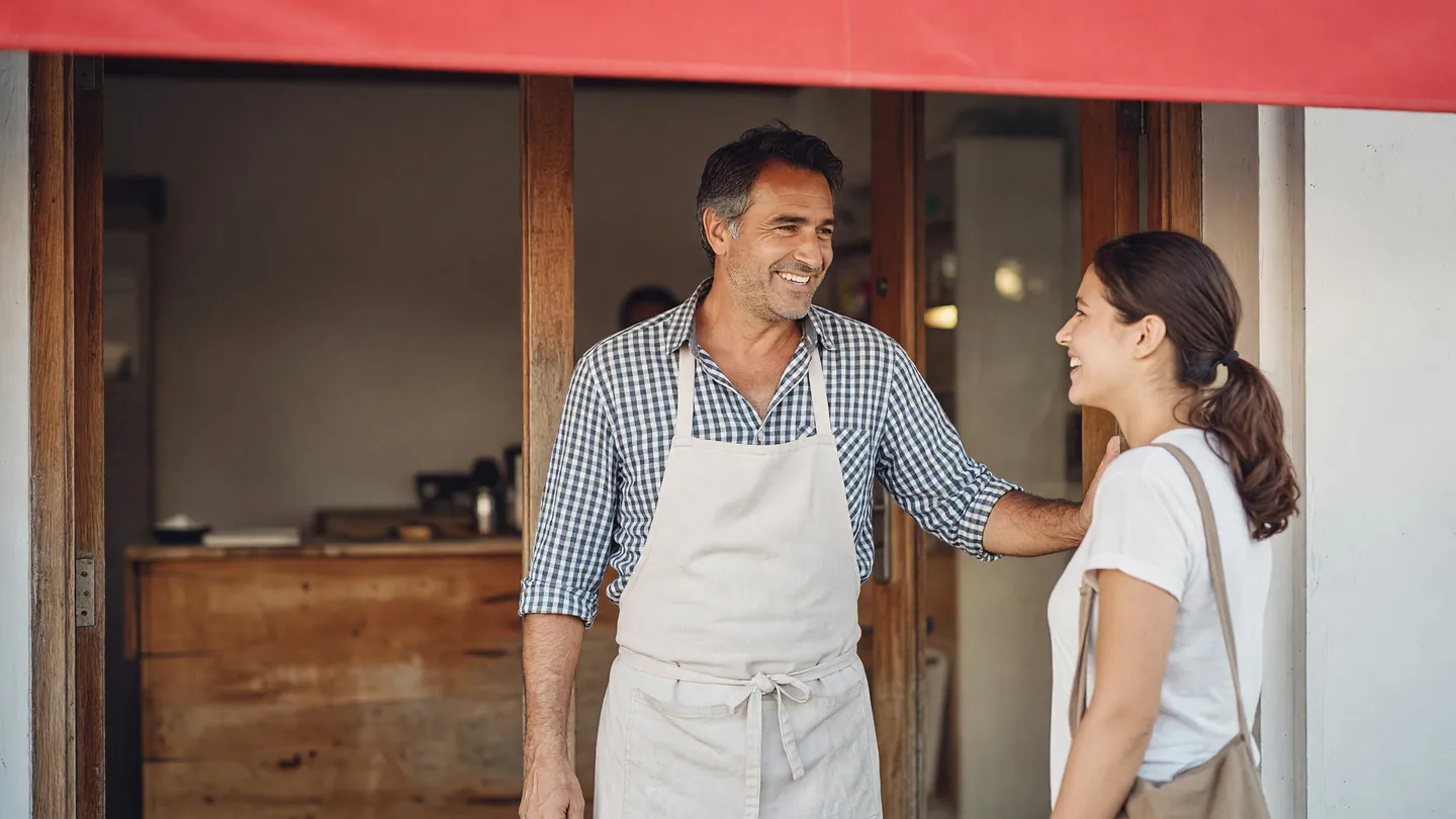 Artigiano saluta un cliente sulla porta del negozio, il momento giusto per chiedere una recensione
